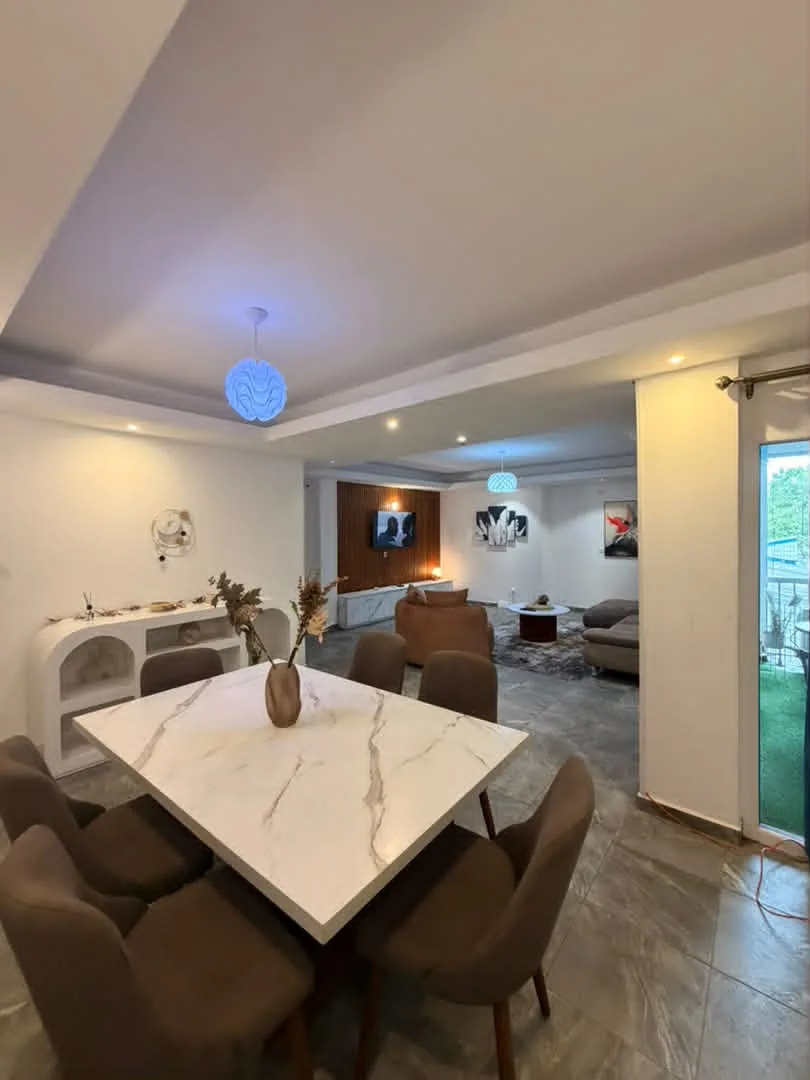 Salle à manger avec table en marbre, salon en arrière-plan