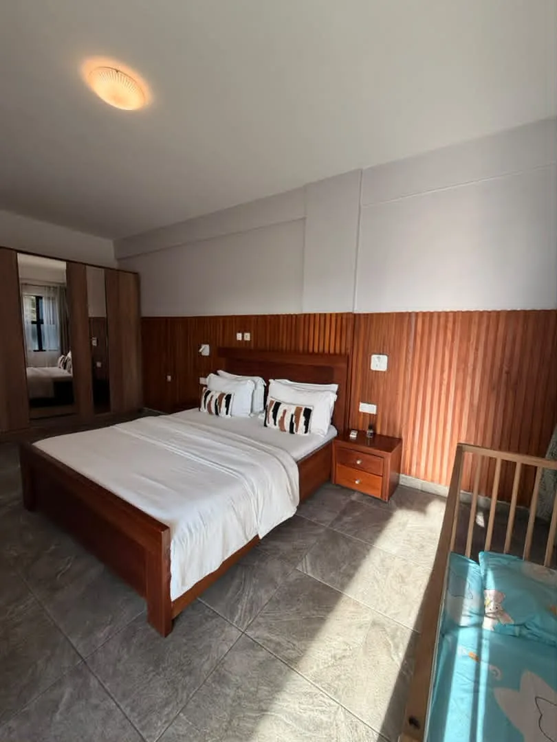 Chambre avec lit double, armoire à miroir et lit de bébé