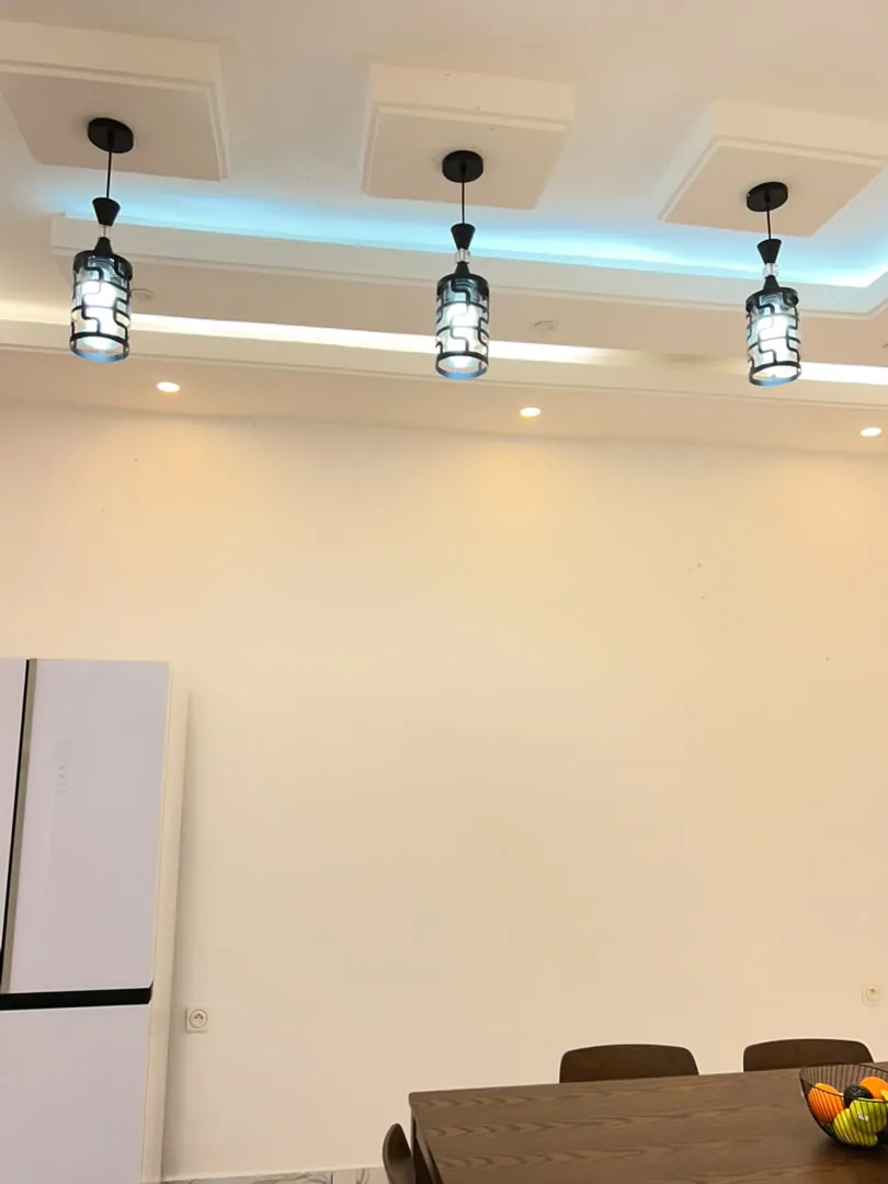 Salle à manger sous des suspensions, réfrigérateur blanc