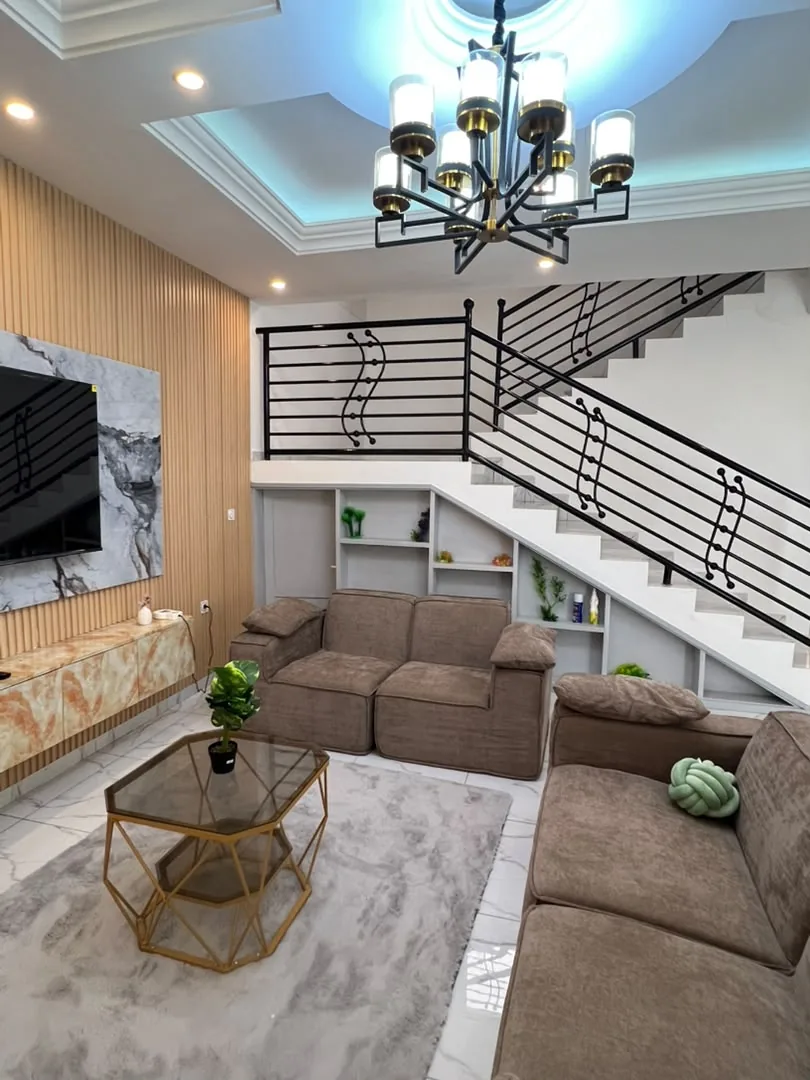 Salon avec canapés, télévision murale et escalier