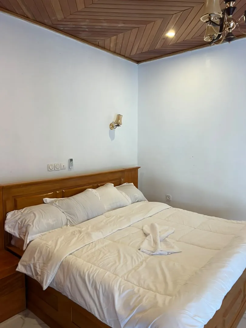 Chambre avec lit double en bois et appliques murales