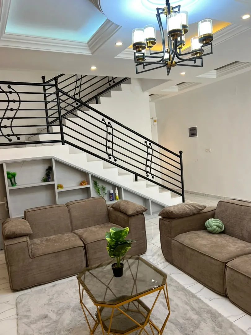 Salon avec canapés et escalier à rampe en fer forgé