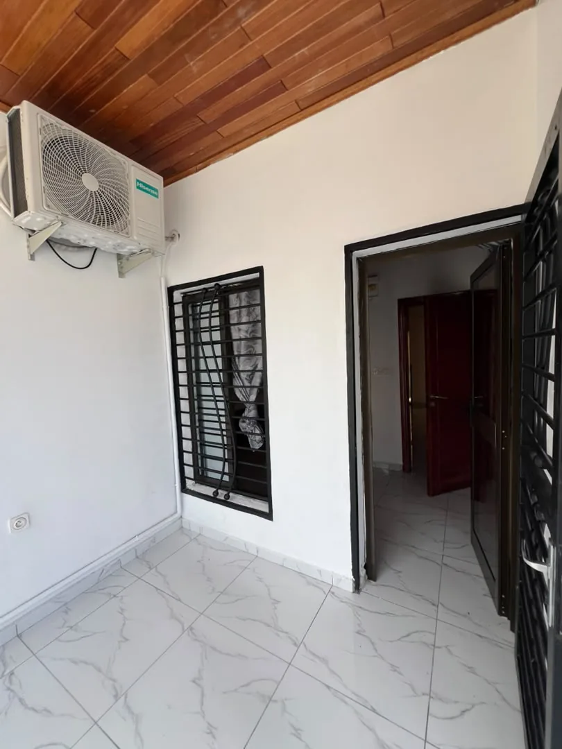 Couloir carrelé avec climatiseur et porte de chambre