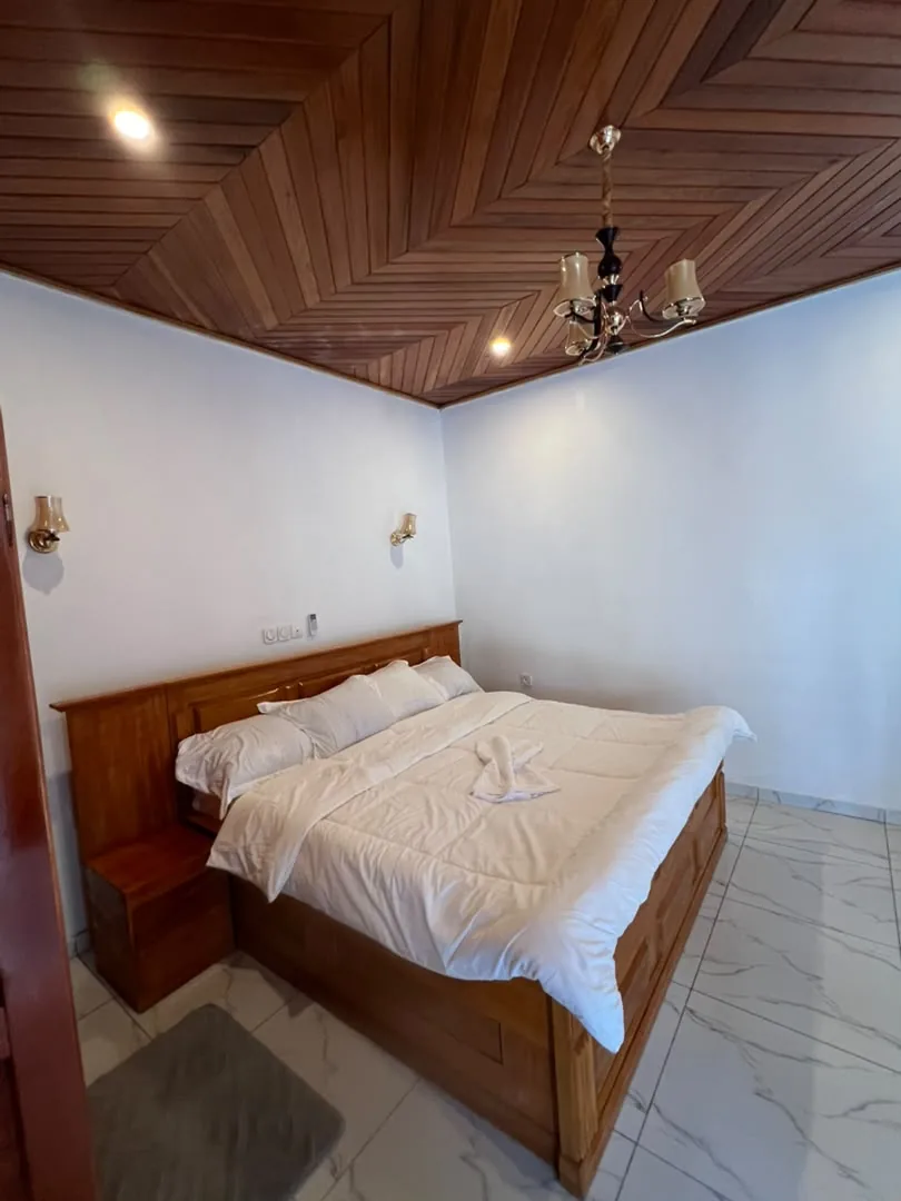 Chambre avec lit double en bois et plafond en lambris