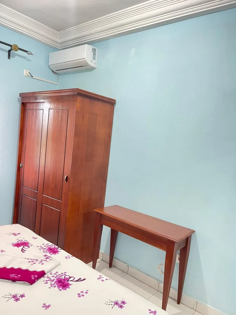 Chambre avec armoire en bois et climatiseur