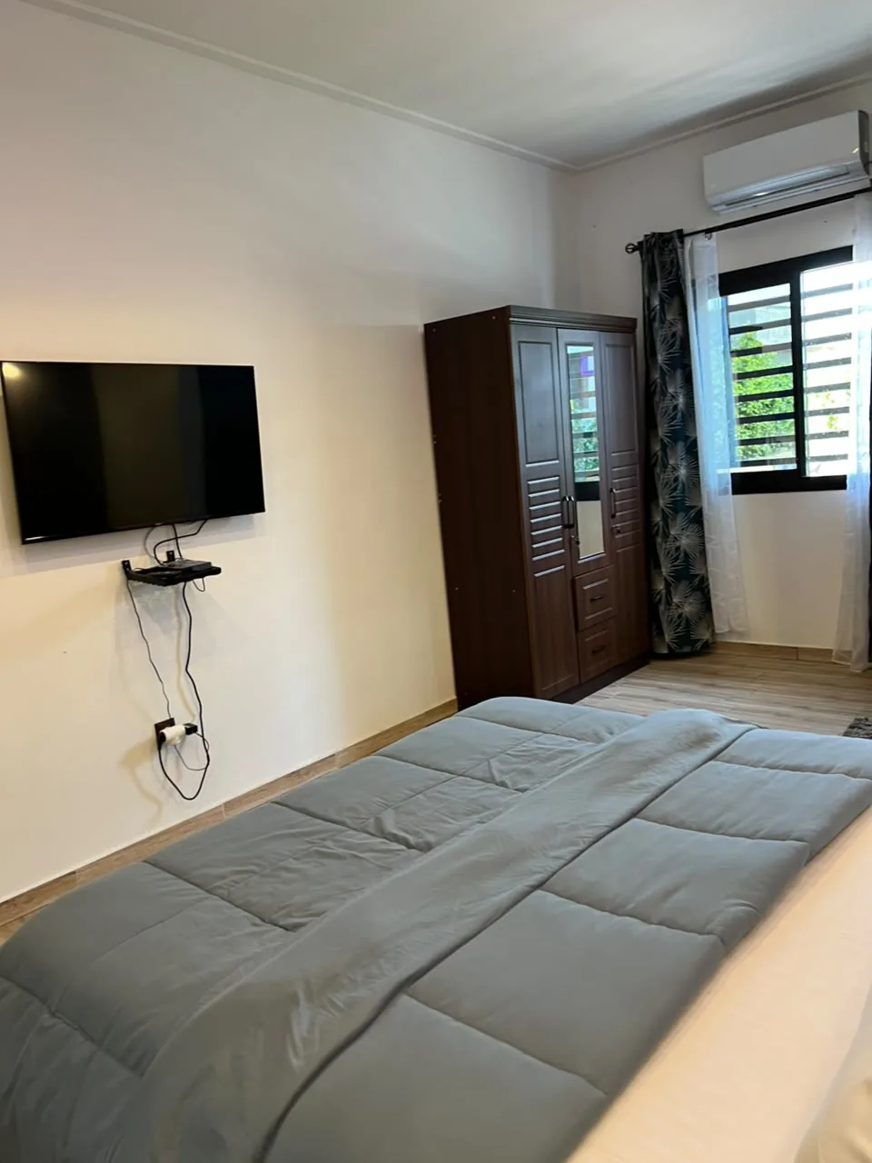 Chambre avec lit, télévision murale et armoire en bois